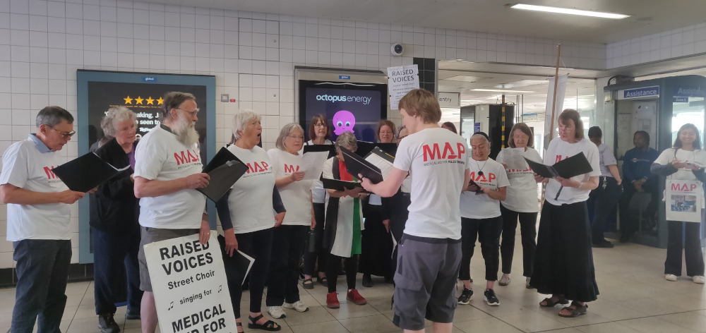 Raised Voices singing at MAP busking, Jake conducts