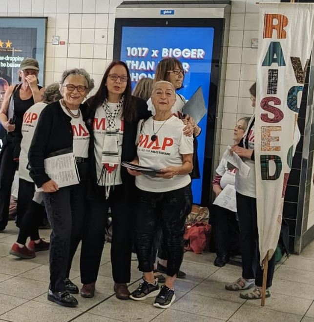 Members of Raised Voices post next to banner